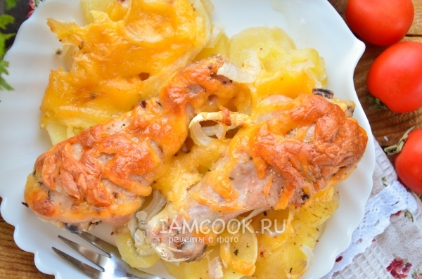 Photo of potatoes with chicken drumsticks and cheese in the oven