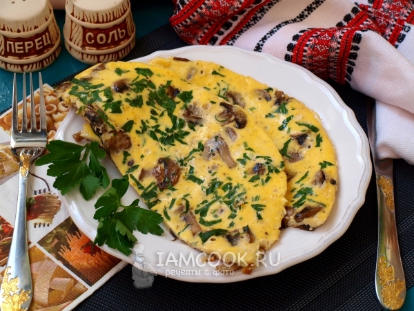 Photo of an omelette with mushrooms in a frying pan
