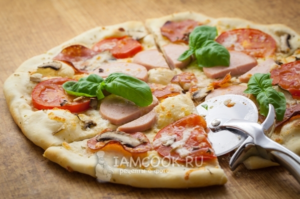 Foto pizza dengan jamur, sosis, tomat, dan keju