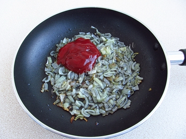 Onions with tomato paste on a frying pan